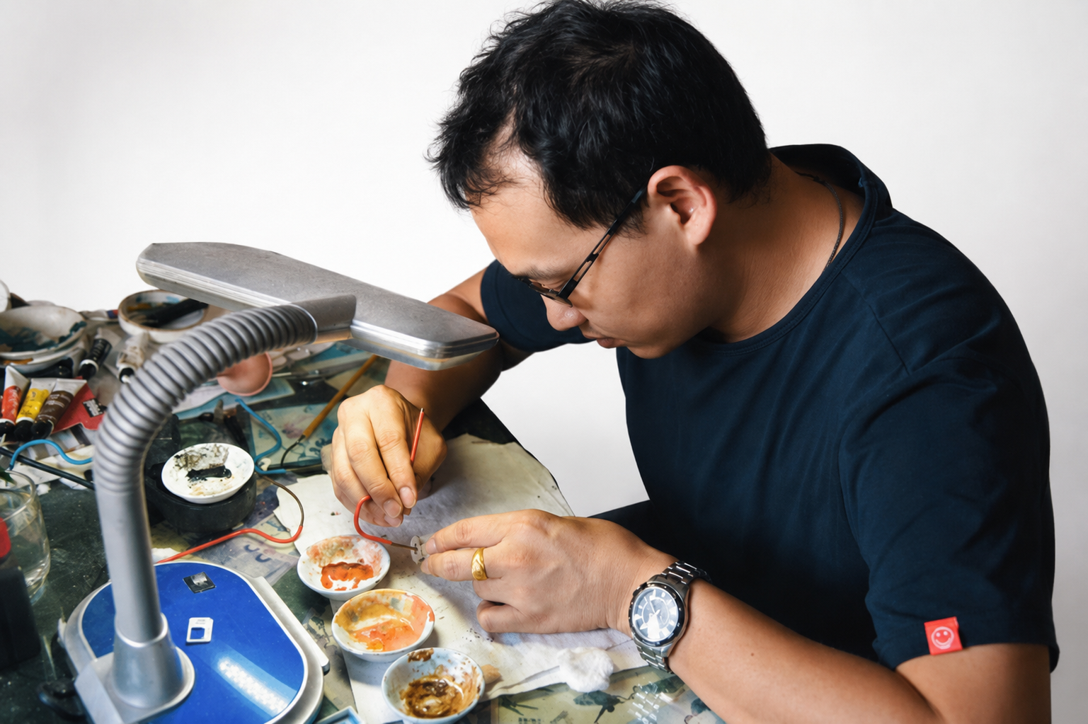 Artist painting at a watchmaking workbench